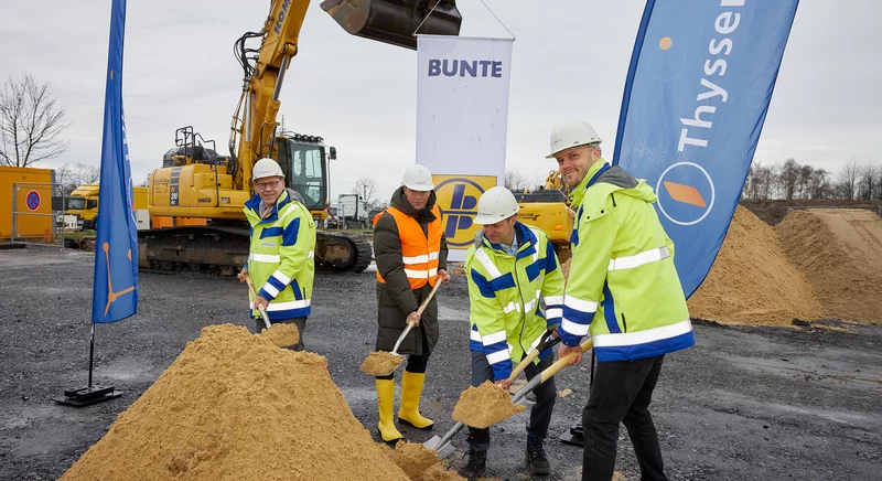 Spatenstich auf einer Baustelle mit Vertretern von Thyssengas und Partnern vor einem Bagger.