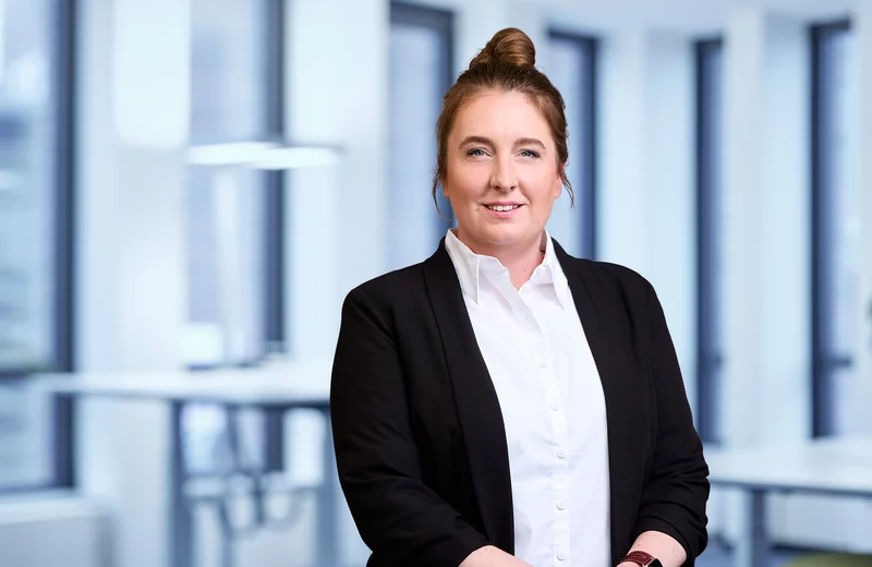 Portrait von Thyssengas-Mitarbeiterin Nadia Sauerland vor modernem Bürohintergrund.