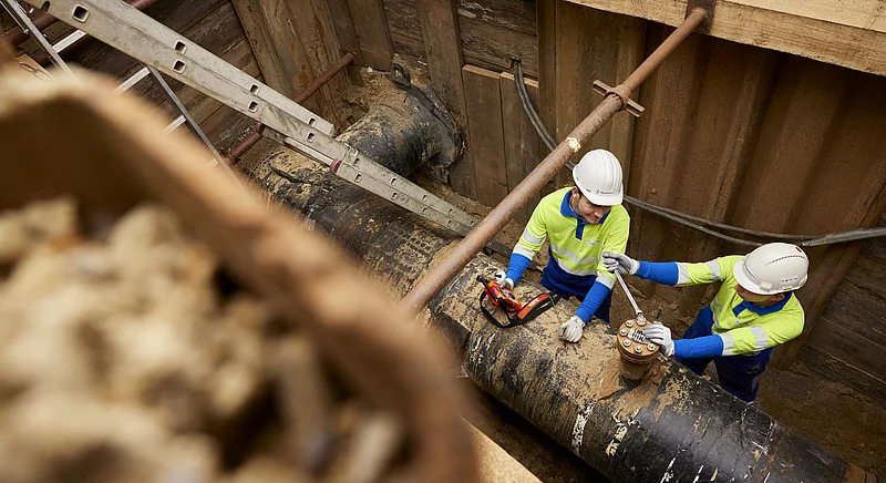 Zwei Thyssengas-Monteure bei Leitungsbauarbeiten an einer Pipeline in einer gesicherten Baugrube.