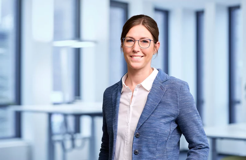 Portrait von Thyssengas-Mitarbeiterin Maike Schikfelder vor modernem Bürohintergrund.