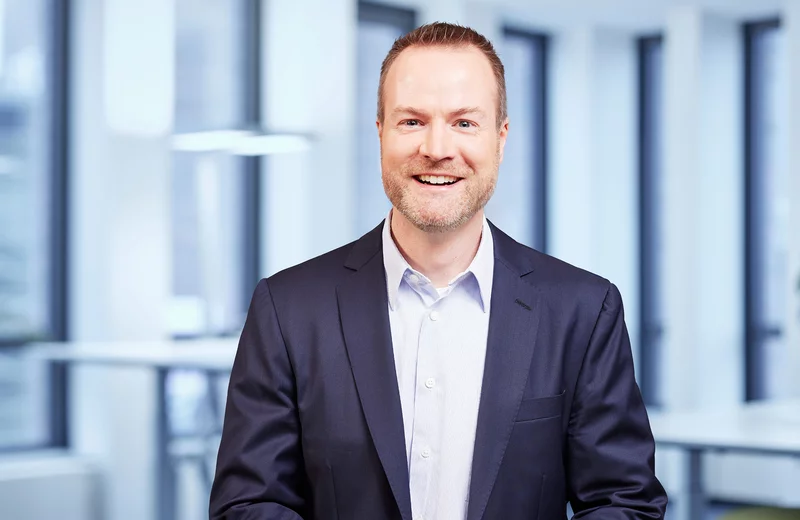 Portrait von Thyssengas-Mitarbeiter Markus Rottmann vor modernem Bürohintergrund.