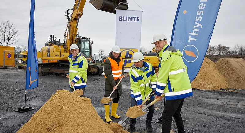 Spatenstich auf einer Baustelle mit Vertretern von Thyssengas und Partnern vor einem Bagger.