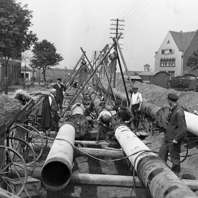 Historische Schwarz-Weiß-Aufnahme zur Verlegung von großen Gasrohren für den Gastransport im frühen 20. Jahrhundert.