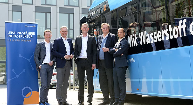 Gruppenfoto von fünf Geschäftspartnern vor einem Wasserstoffbus, neben einem Thyssengas-Banner für H2-Infrastruktur.