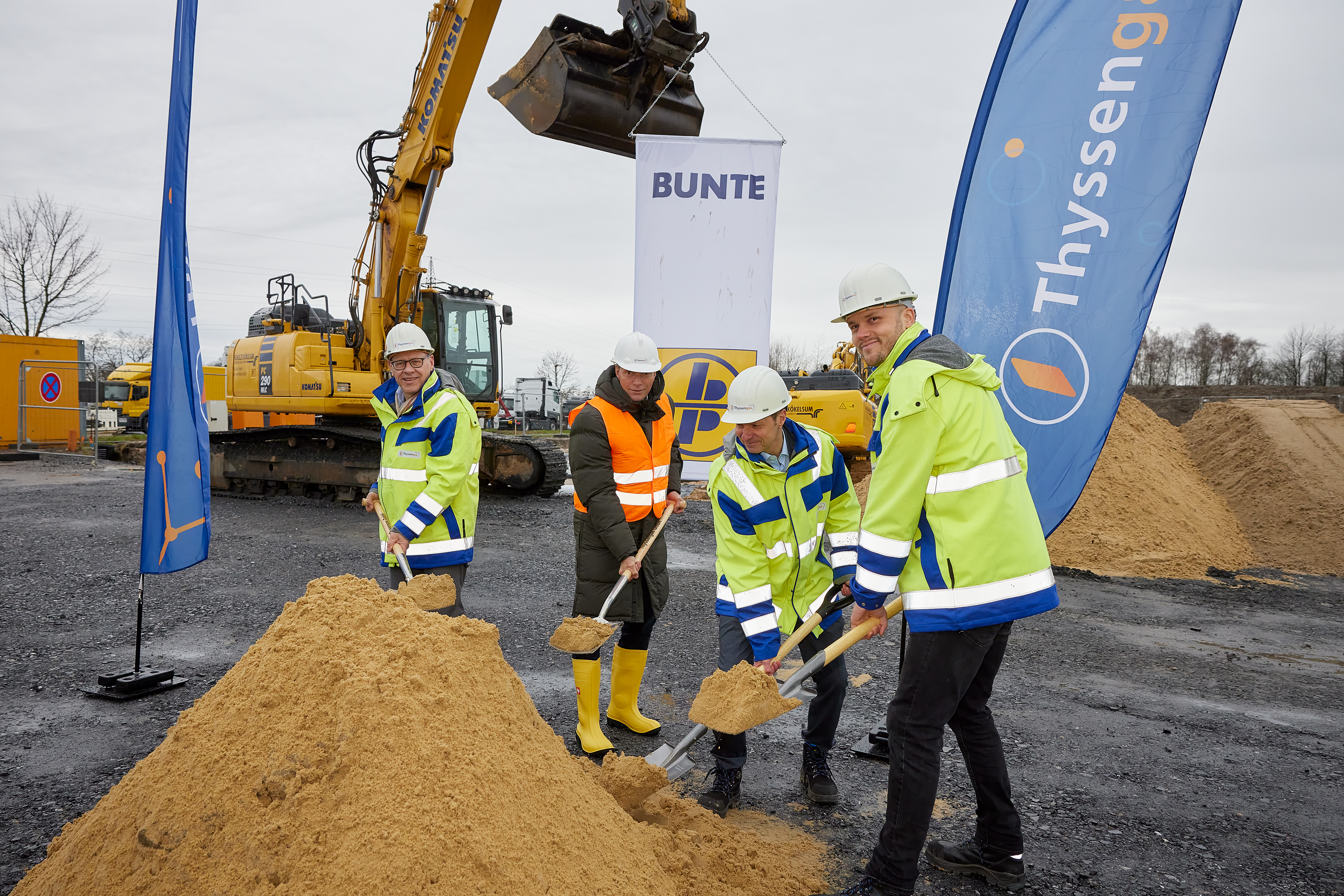 Spatenstich auf einer Baustelle mit Vertretern von Thyssengas und Partnern vor einem Bagger.
