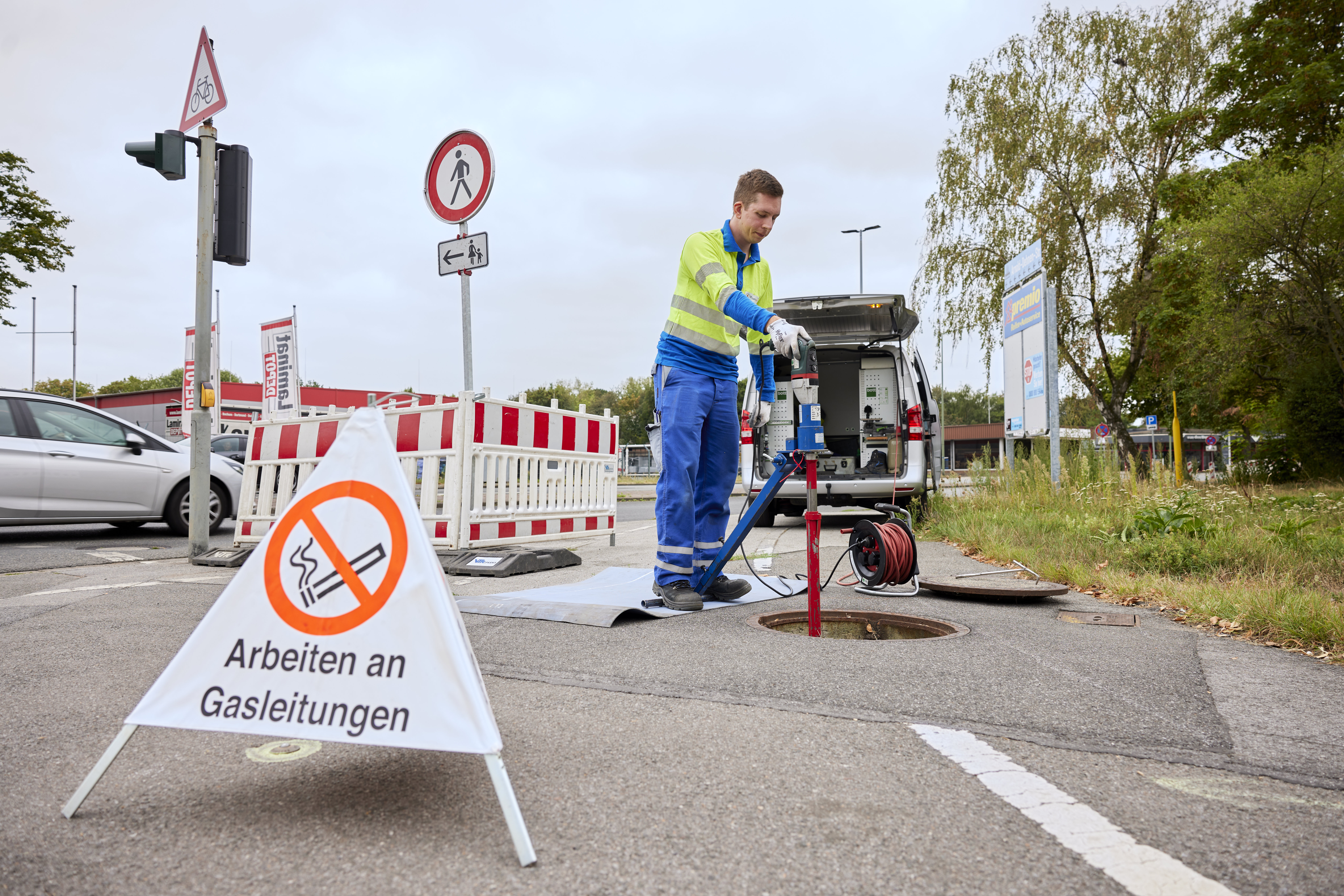 Thyssengas-Techniker bei Arbeiten an einer Gasleitung mit Warnschild und geöffnetem Kanalschacht an einer Straße.